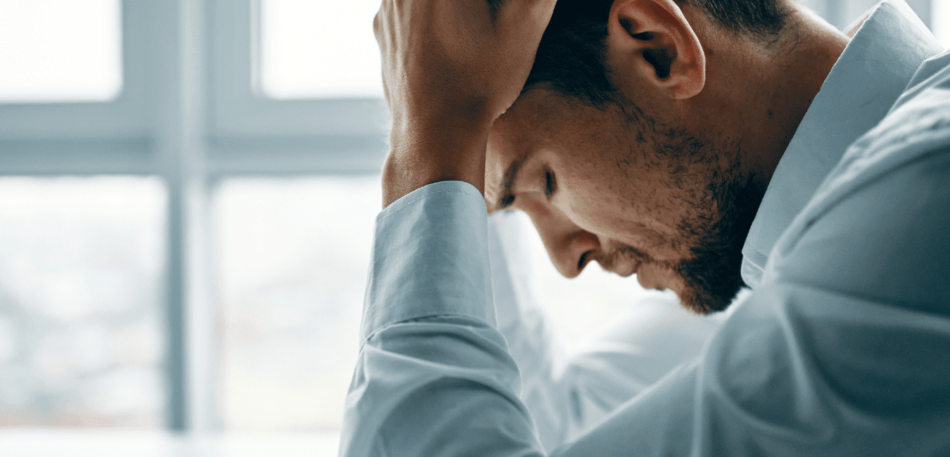 Man looking depressed sitting on the floor with head down in office