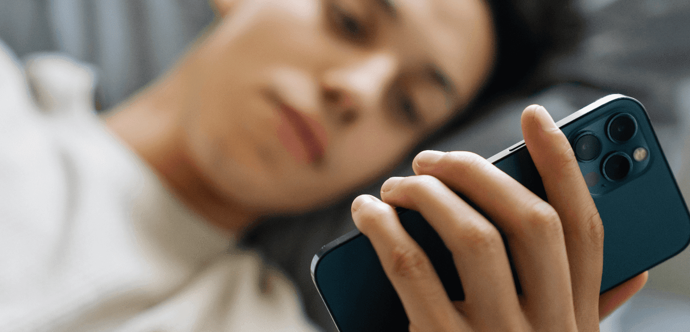 Young man lying on bed at his room using his phone