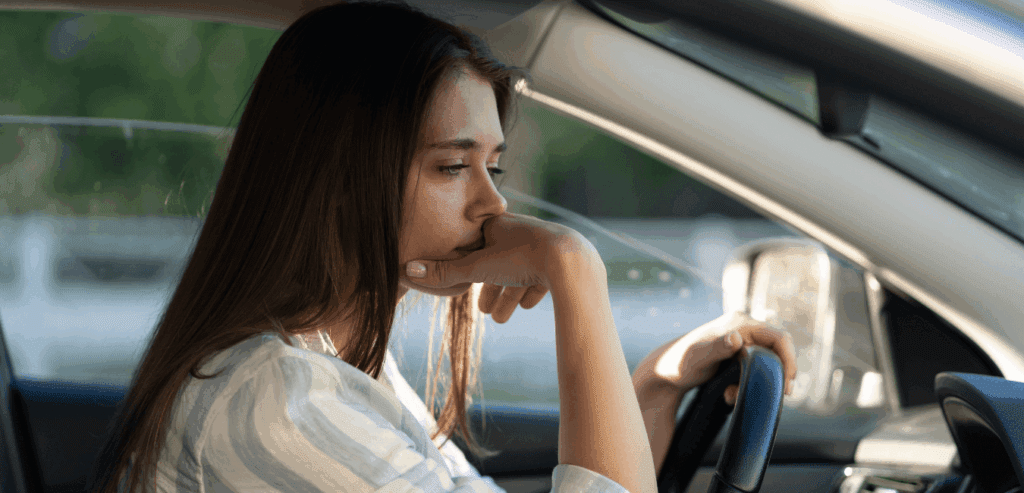 Woman driver alone in her car looking sad reflecting quitely