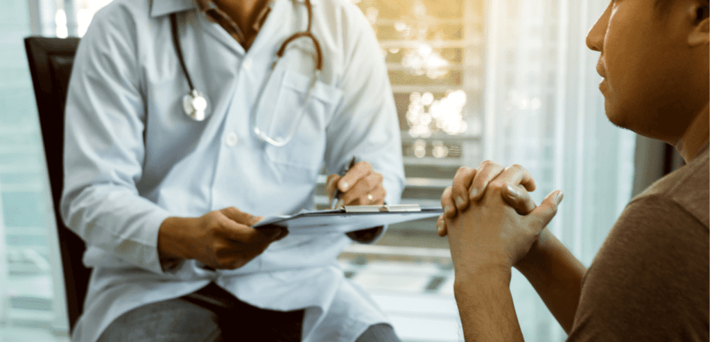 Man talking to a doctor holding a pen and a paper for some questions