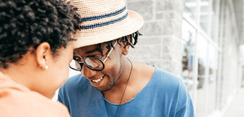 Young African couple in vacation, man wearing blue shirt and fedora hat with their heads together