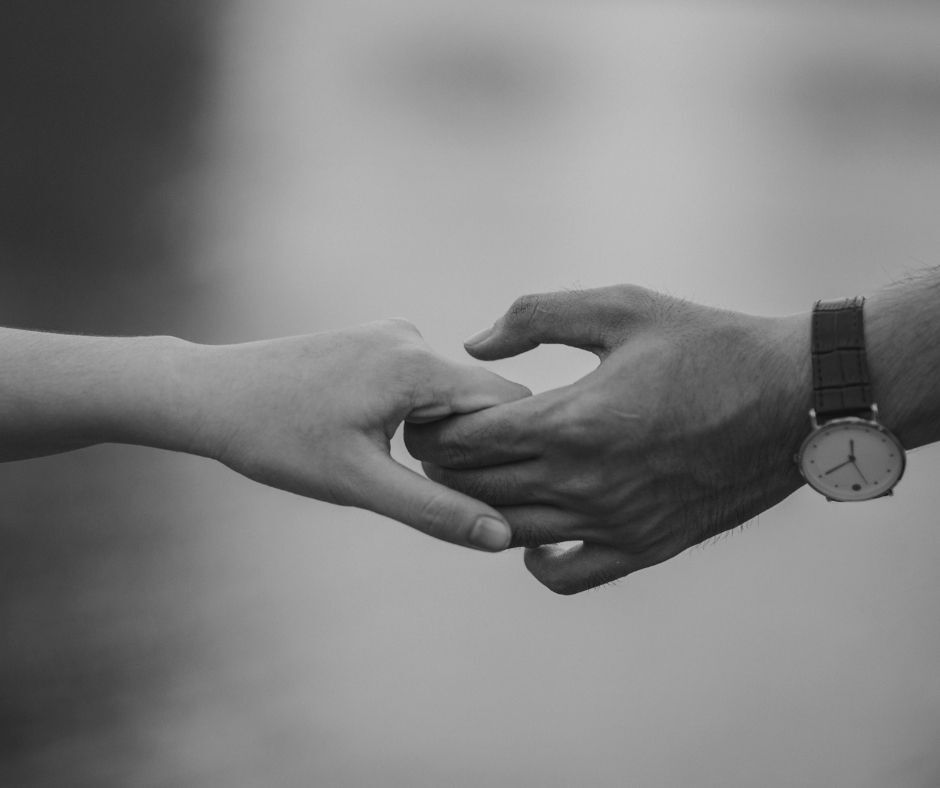 Two hands, one from each person in a relationship losing their grasp.