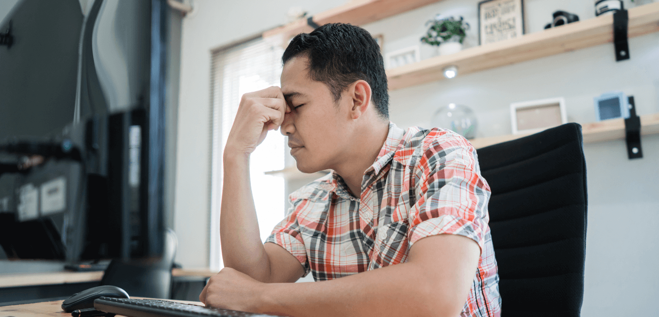 Man on his desk with hand on his face looking unhappy