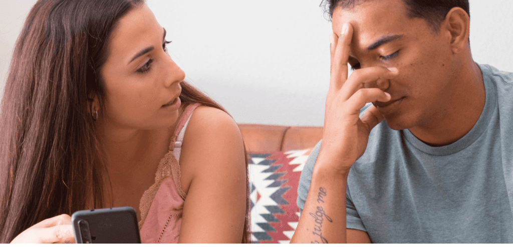 Young couple sitting on couch at home having a conversation looking like having a problem