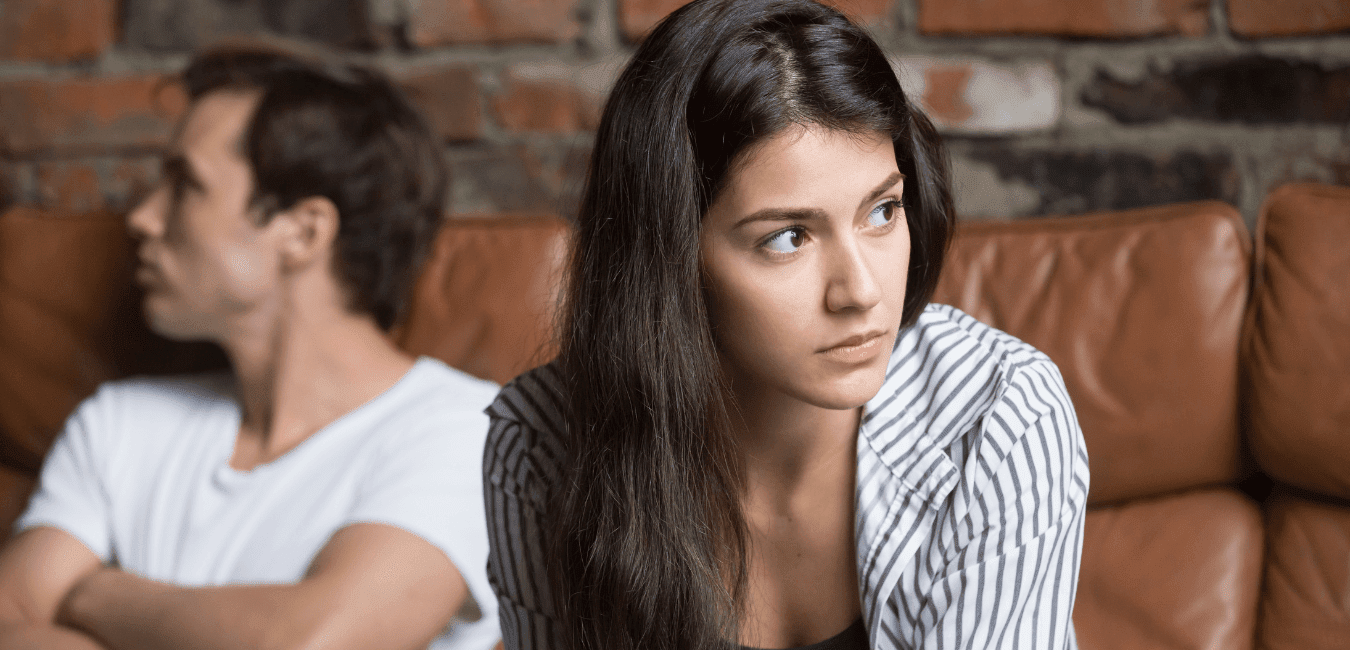 Young couple sitting on leather couch not talking looking at opposite direction