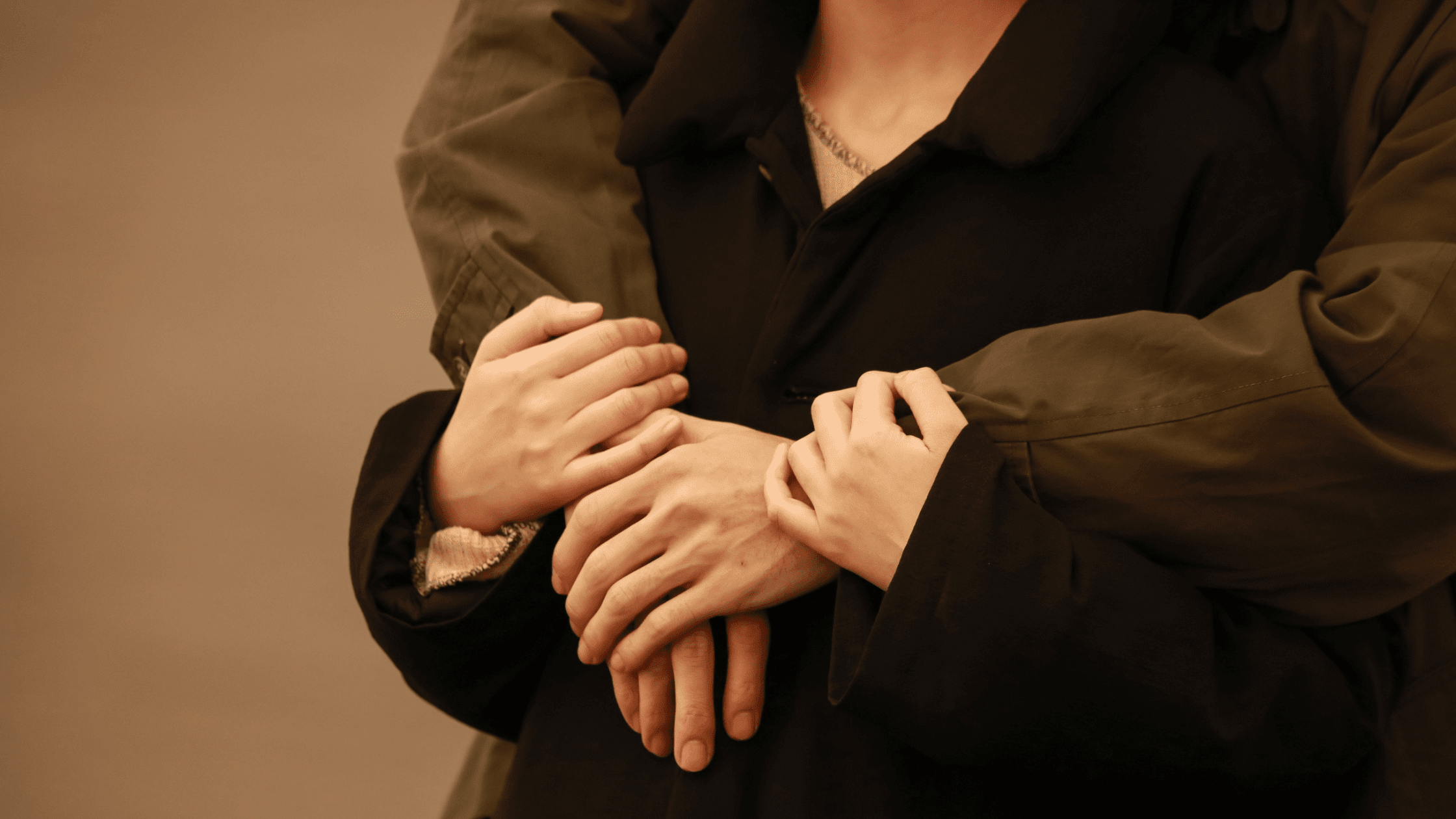 Close-up shot of a man hugging his partner outdoors at sunset.