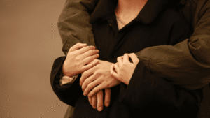 Close-up shot of a man hugging his partner outdoors at sunset.
