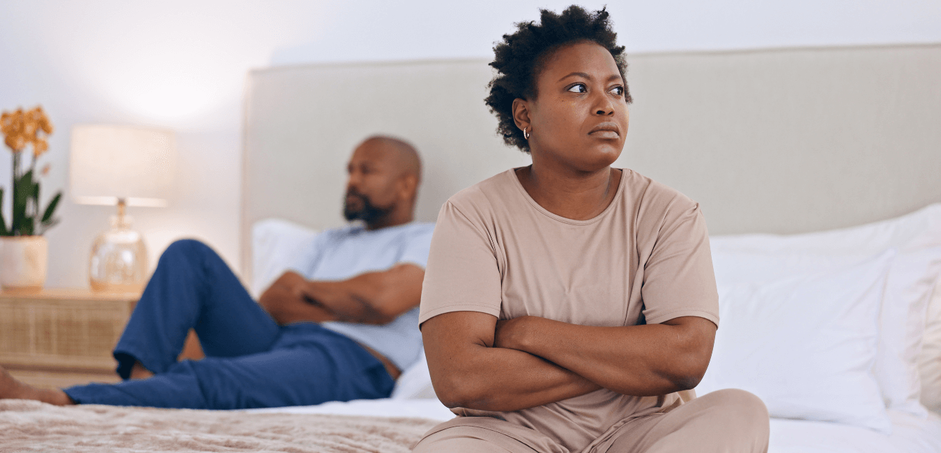 Couple sitting on bed looking away not talking after fight