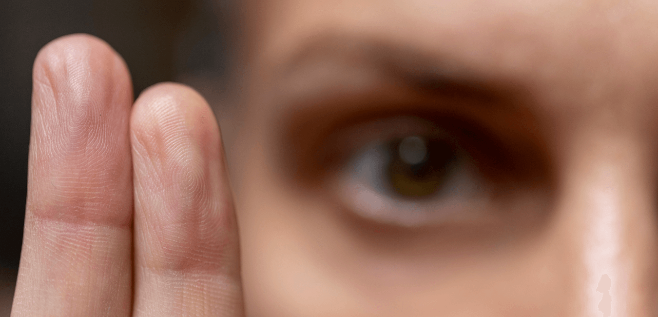 Close up photo of woman's hands showing only two finger and one eye