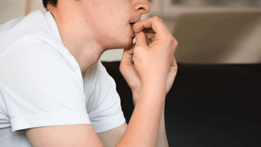 Close-up of a man with an anxious expression, biting his nails