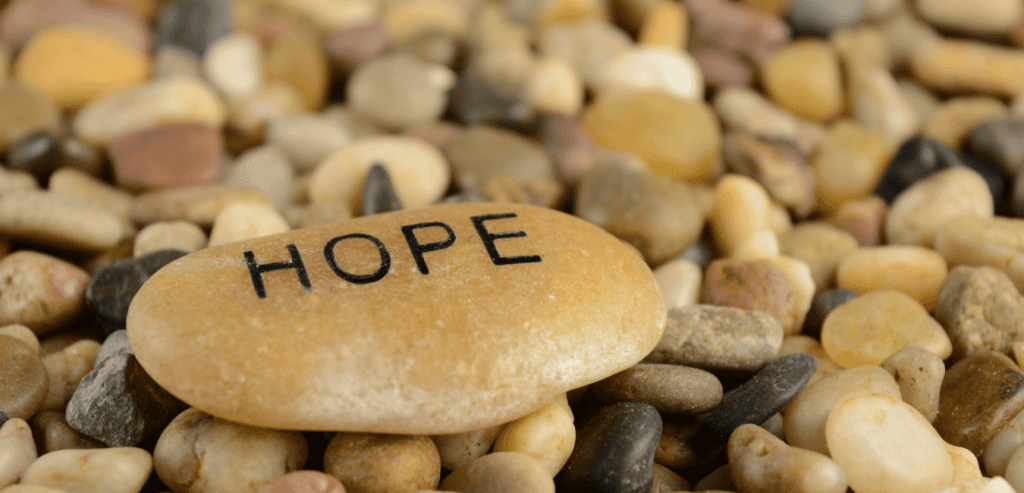 A pile of small rocks with one larger on top that says, "Hope"