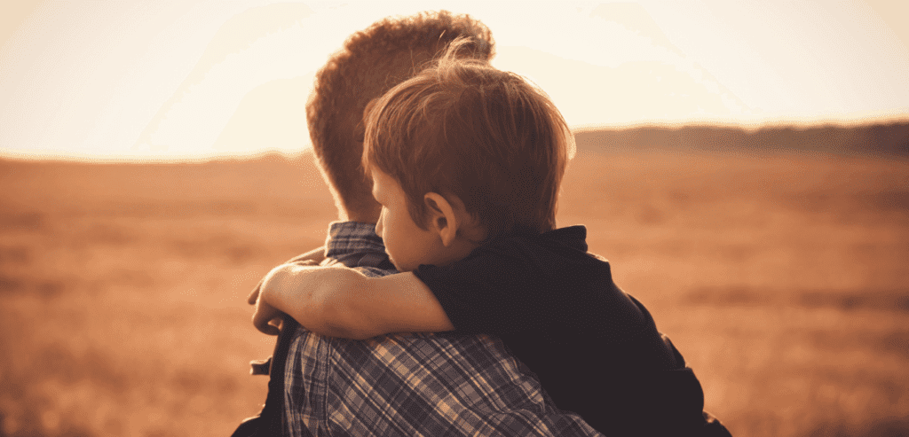 Man carrying his child in outdoors at sunset