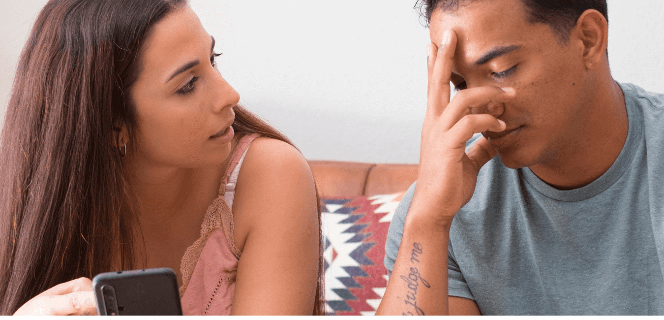 Young couple sitting on couch at home having a conversation looking like having a problem