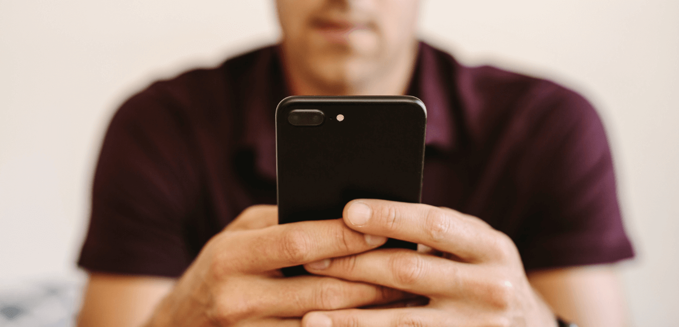 Close up photo of a man sitting looking focused holding a mobile phone