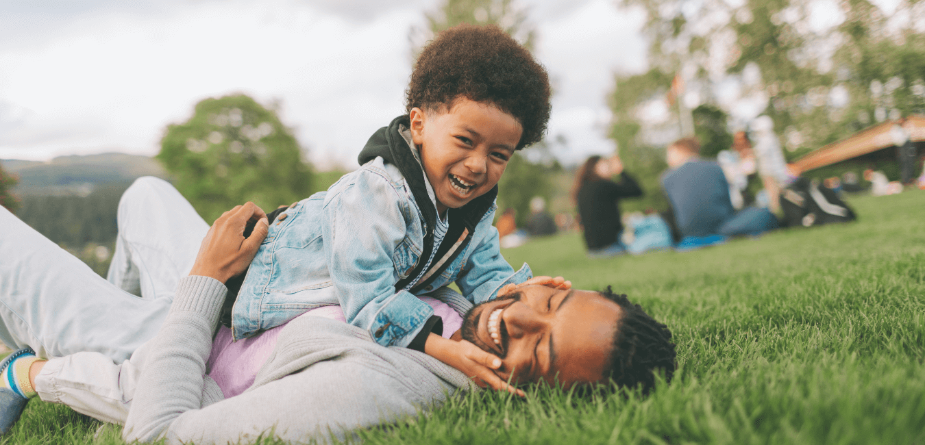 Father and son laughing and bonding while playing at the park.