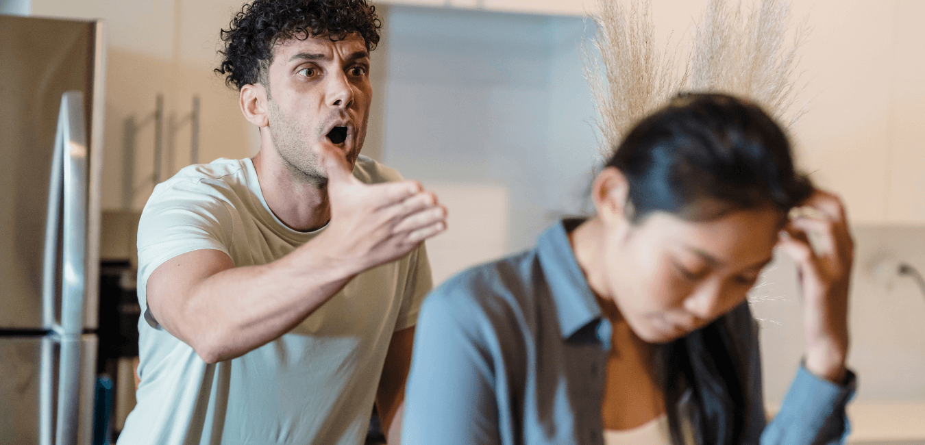 Young couple in a tense argument in living room, both appearing upset and emotionally charged
