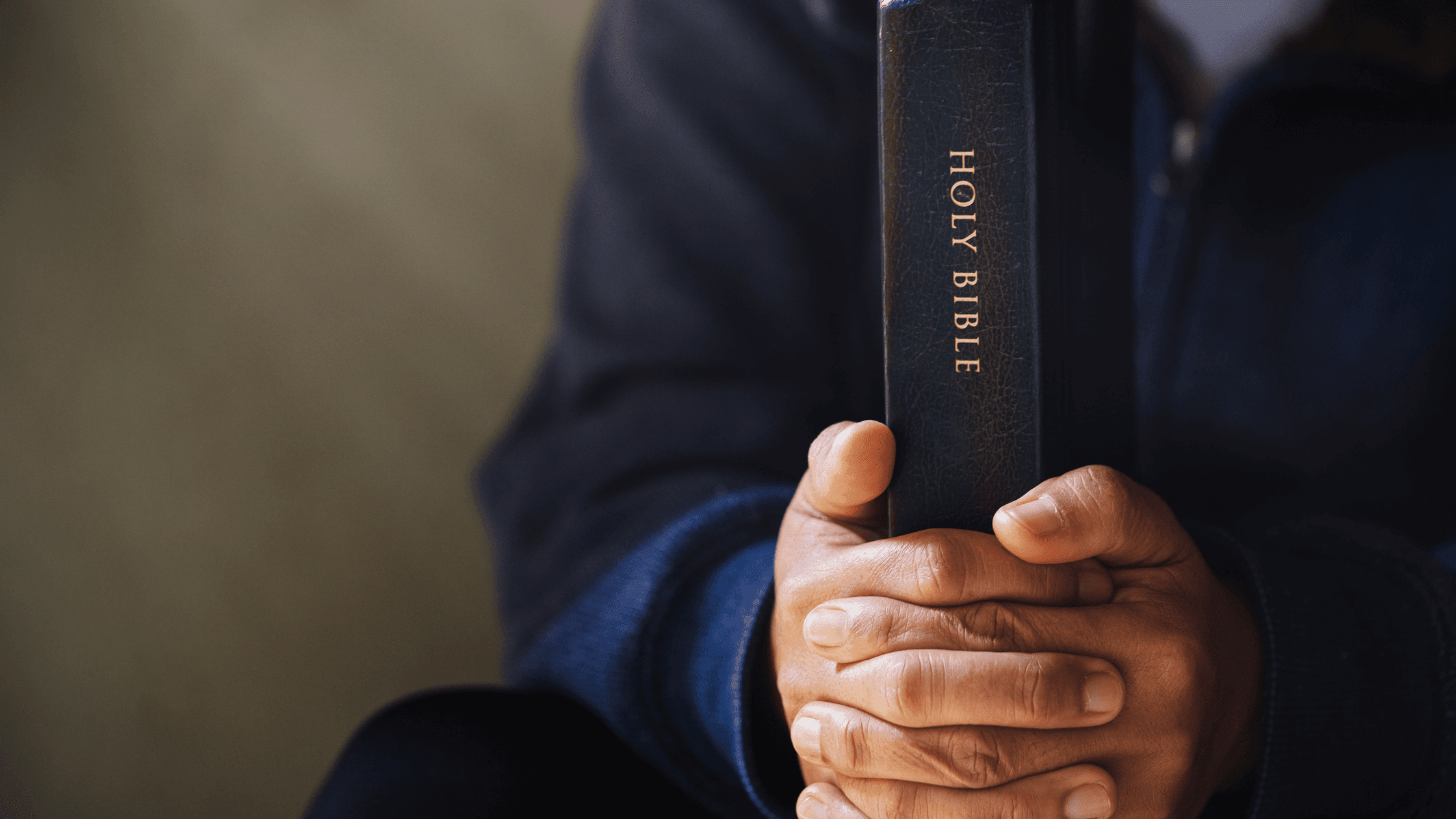 Close-up of Holy Bible held by man sitting