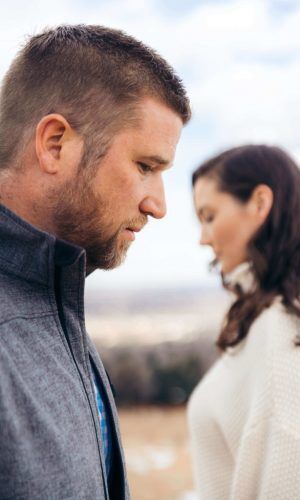 A man and woman both looking down at the ground the man in front the woman in the back