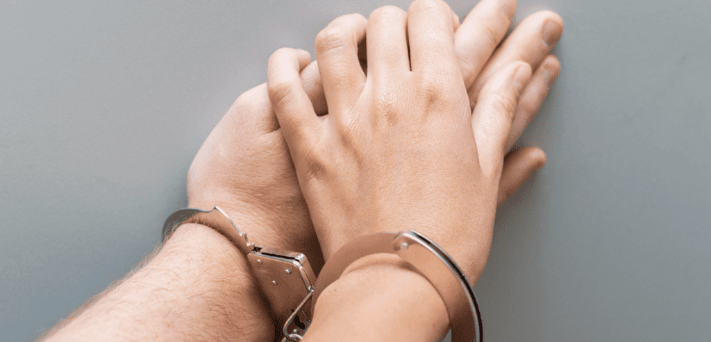 Hand of a man and a woman in metal handcuffs close-up. Codependency concept