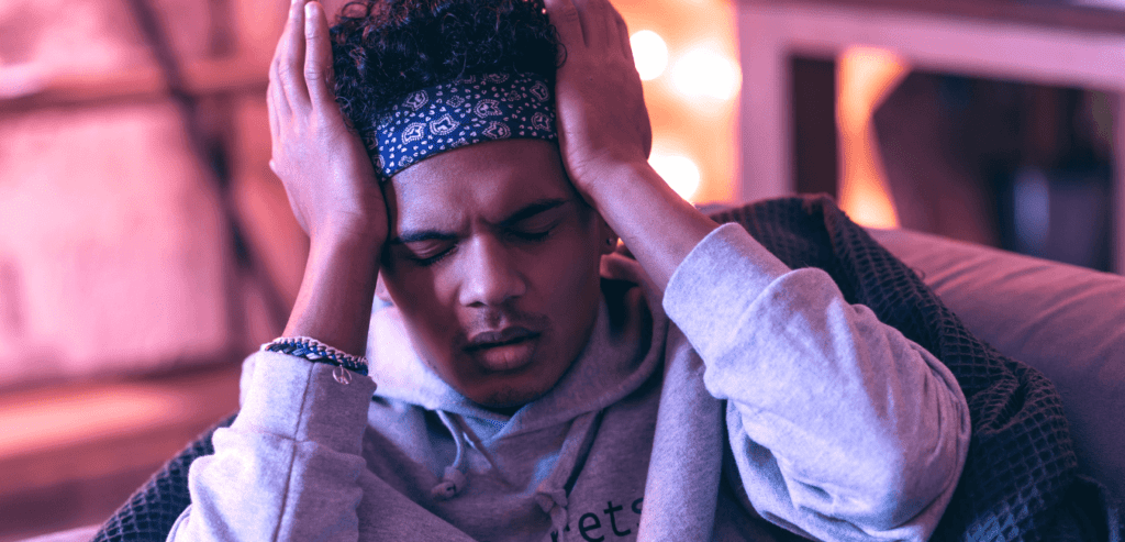 Man sitting on couch at home holding his head having a headache