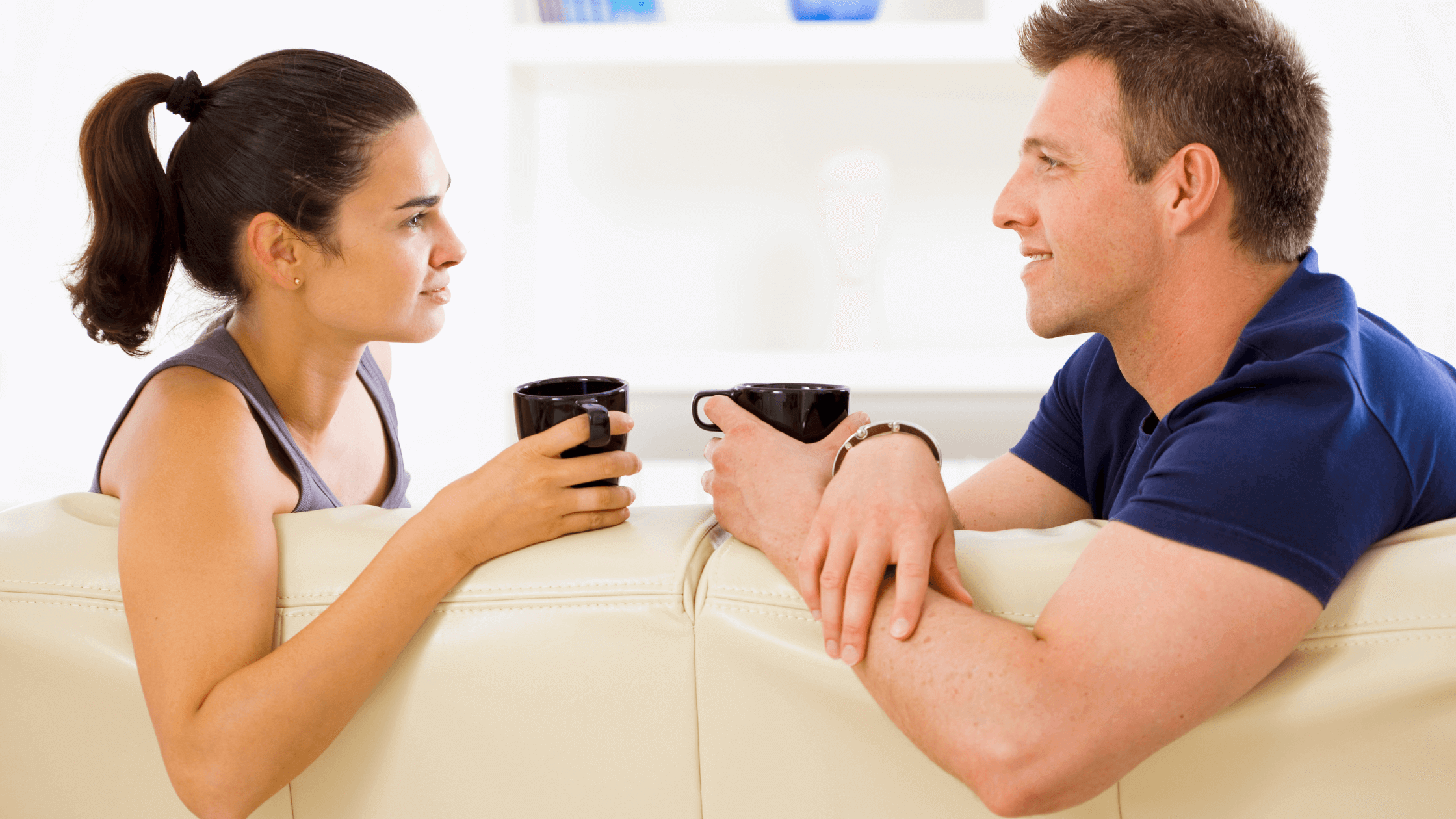 Couple sitting on a couch, talking while holding a mug