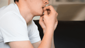 Close-up of a man with an anxious expression, biting his nails