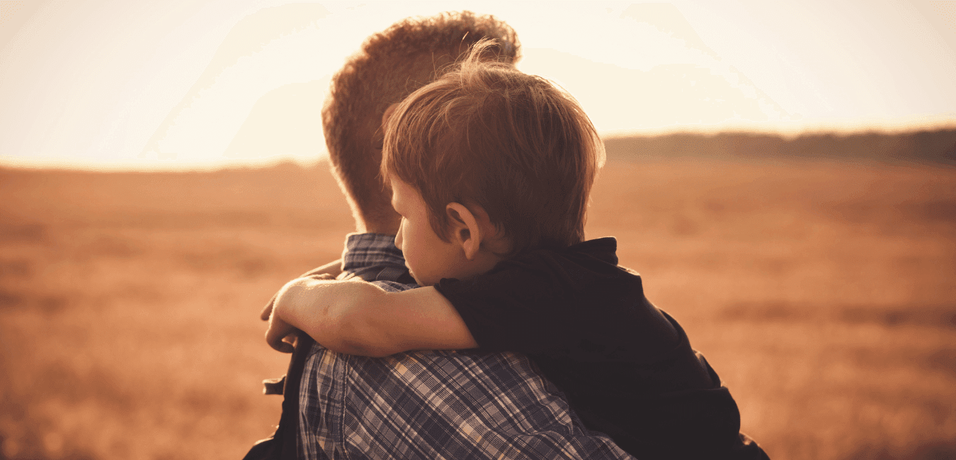 Man carrying his child in outdoors at sunset