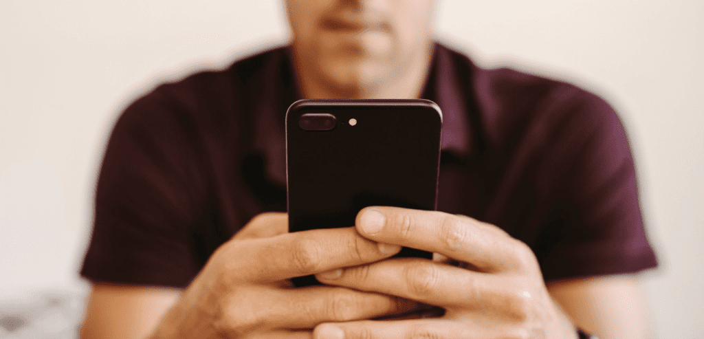 Close up photo of a man sitting looking focused holding a mobile phone
