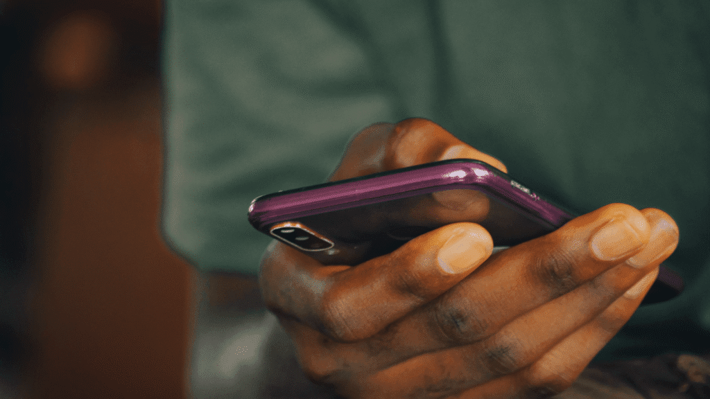 Focused shot of a man of color using a mobile phone, appearing concentrated.