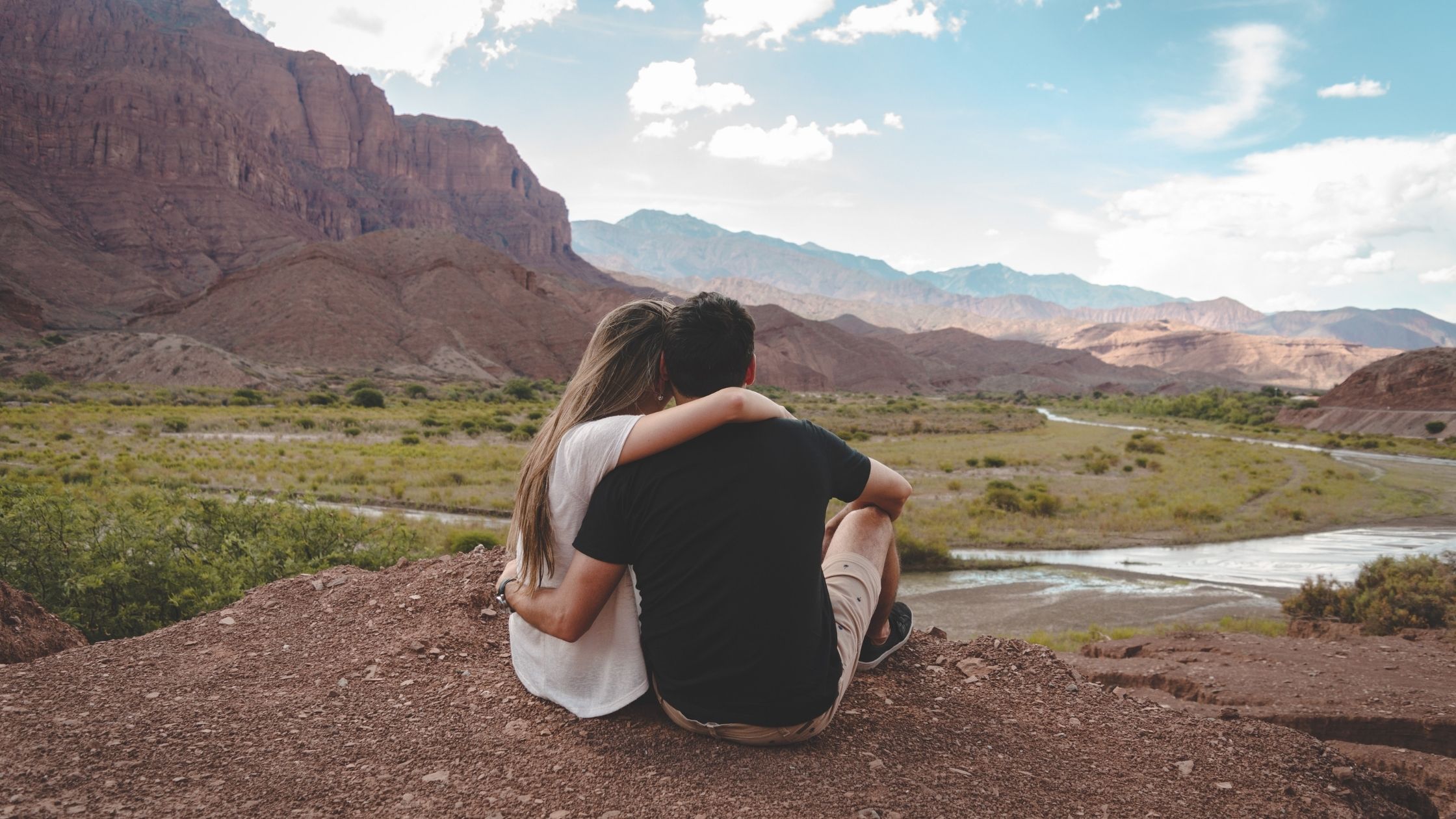 A couple sitting while looking over a mountainous landscape
