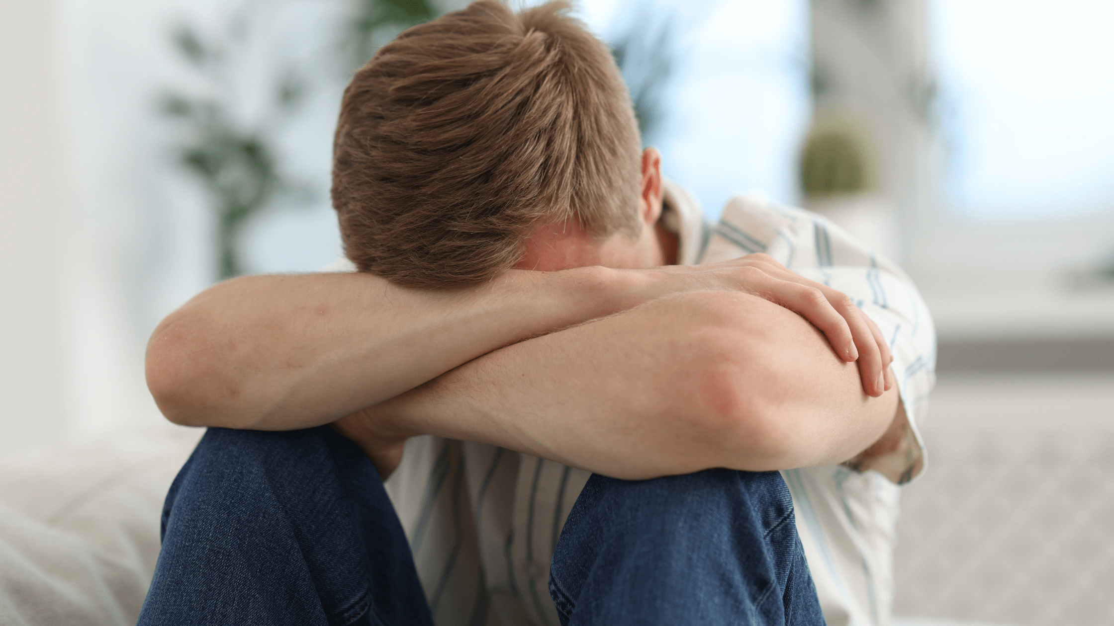 Man on sofa, head lowered, sitting quietly as if thinking deeply