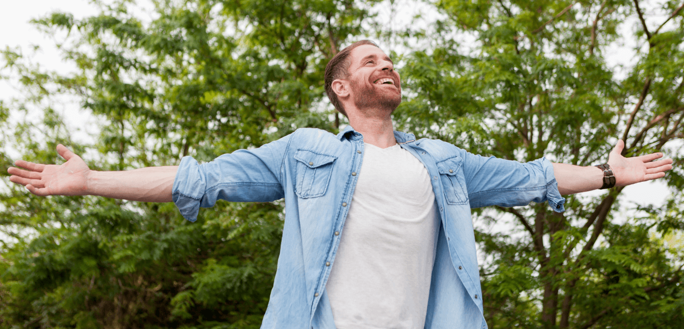 Man in open air outdoors looking happy with arms wide open